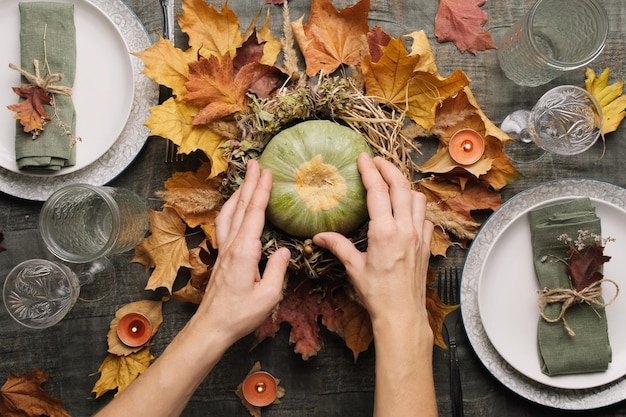 Autumn table setting Hands makes autumn arrangement with pumpkin for thanksgiving feast