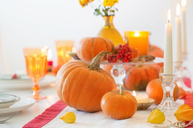 Autumn table setting with burning candles and pumpkins