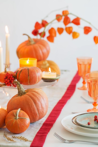 Autumn table setting with burning candles and pumpkins