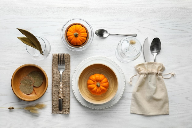 Autumn table setting with pumpkins on white wooden background flat lay