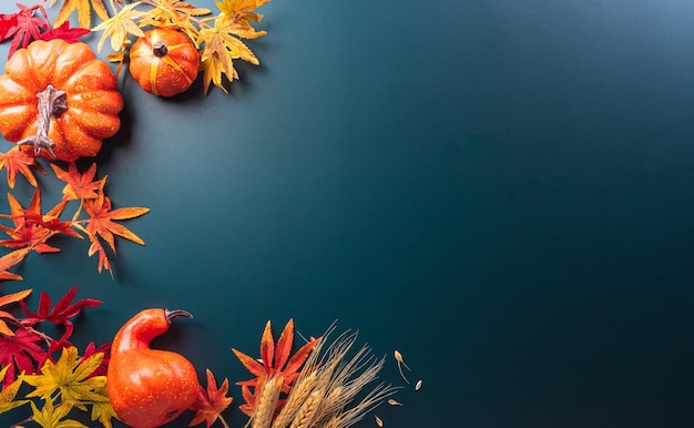 Autumn and thanksgiving decoration concept made from autumn leaves and pumpkin on dark background Flat lay top view with copy space