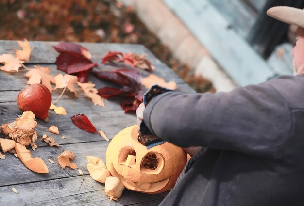 Autumn traditions and preparations for the holiday Halloween. A house in nature, a lamp made of pumpkins is cutting out at the table.