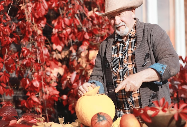 Autumn traditions and preparations for the holiday Halloween. A house in nature, a lamp made of pumpkins is cutting out at the table.