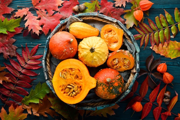 Autumn vegetables Colored pumpkins with autumn leaves flat lay On a blue wooden background Top view Free space for your text