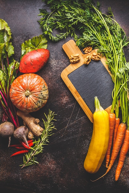 Autumn vegetables table. Pumpkin, zucchini, sweet potatoes, carrots and beets on dark table.