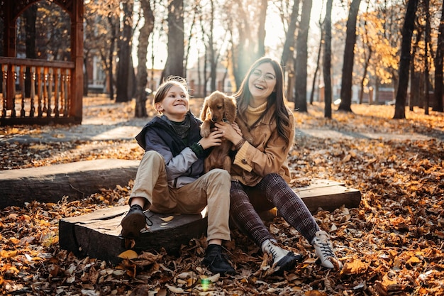 Autumn walks with dog happy family mother and teen boy son having fun with cute cocker spaniel puppy