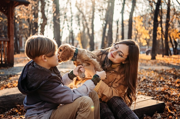 Autumn walks with dog happy family mother and teen boy son having fun with cute cocker spaniel puppy