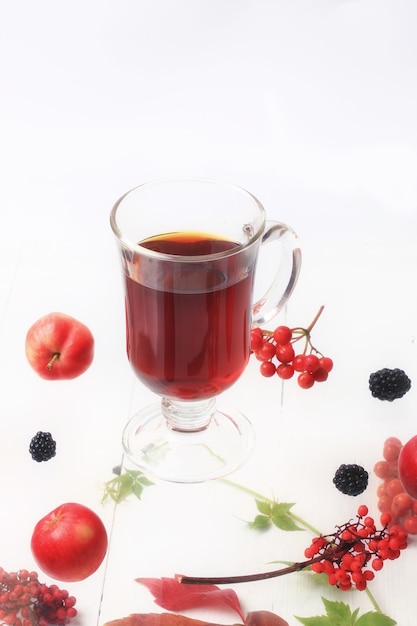 Autumn warming tea with berries on a white wooden background