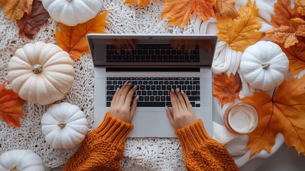 Autumn workspace with a laptop surrounded by decorative pumpkins and colorful leaves in a cozy setting