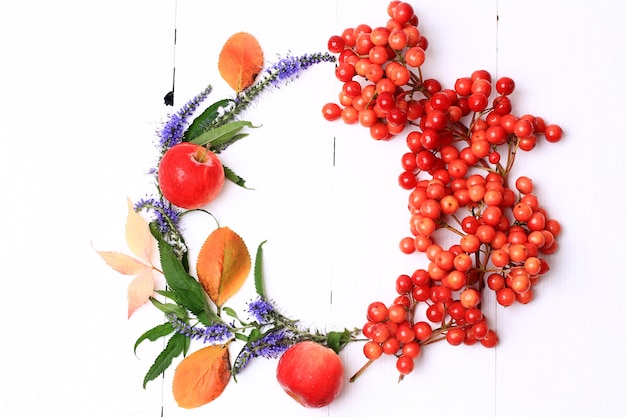 Photo autumn wreath decorated with berries fruits leaves and flowers on white wooden background view from above