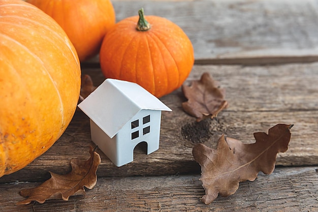 Autumnal Background Toy house and pumpkin on wooden background Thanksgiving banner copy space Hygge mood change of seasons concept Hello Autumn with family Halloween party