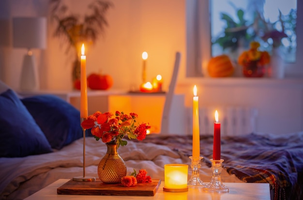 Autumnal chrysanthemum in vase with burning candles in bedroom