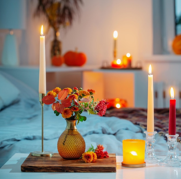 Autumnal chrysanthemum in vase with burning candles in bedroom