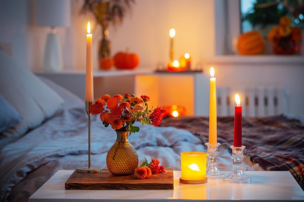 Autumnal chrysanthemum in vase with burning candles in bedroom