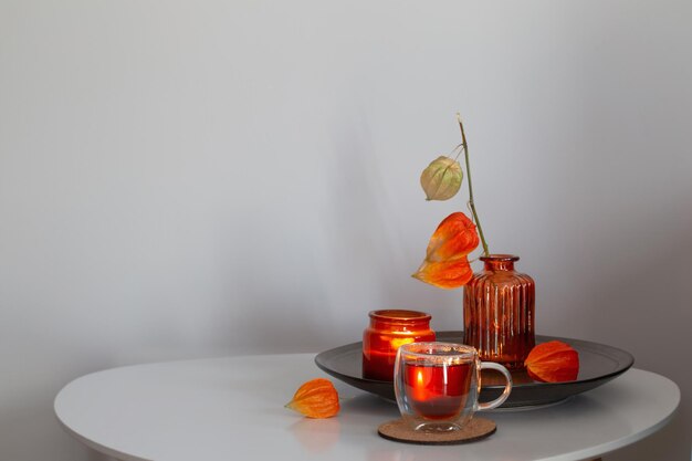 autumnal still life with flowers candles and cup of tea on white table