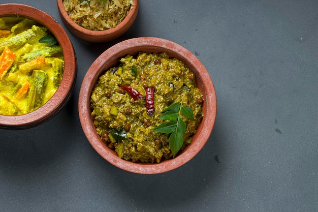 AvialKootu curry and Cabbage fryKerala traditional  side dishes which  is very healthy and tasty vegeterian  dishes arranged in an earthenwares with grey coloured background