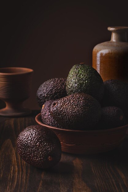 Avocado in a clay plate against a dark and moody wooden backdrop