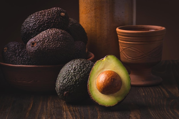 Avocado in a clay plate against a dark and moody wooden backdrop