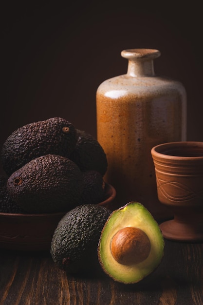 Avocado in a clay plate against a dark and moody wooden backdrop