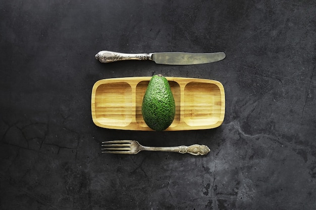 Avocado cooking recipes. Ripe green avocado on a wooden cutting board for serving.