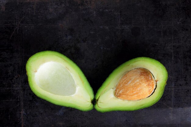 Avocado on dark background Avocado halves on vintage surface Vegetarian food Copy space