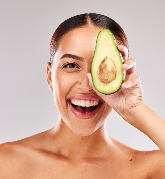 Avocado portrait and woman with natural skincare for wellness beauty and nutrition against a grey studio background Food healthcare and excited model with healthy diet for body and lifestyle