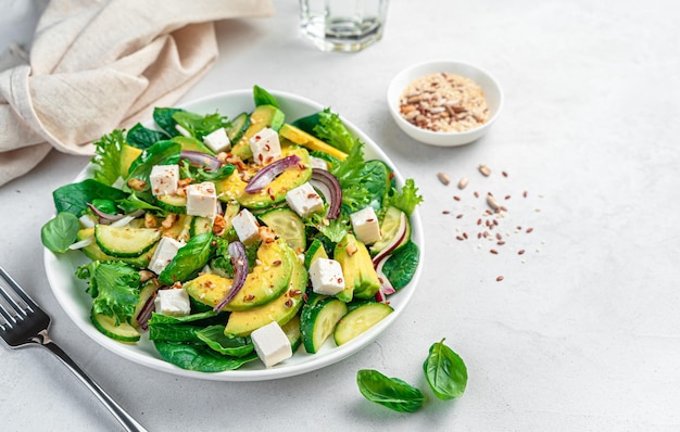 Photo avocado salad with cucumbers feta and nuts on a gray background side view copy space