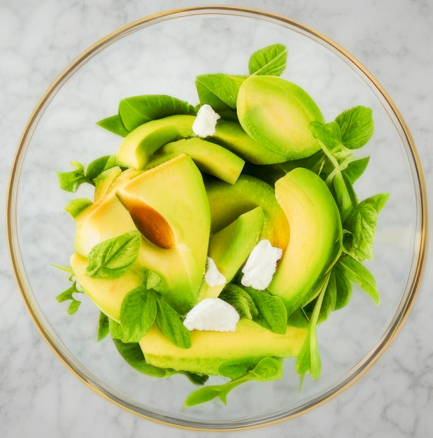 Avocado slices fresh delicious green salad in glass bowl on grey marble kitchen table helthy food