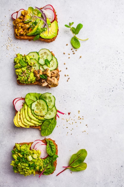 Avocado toasts with different toppings, top view, white background.