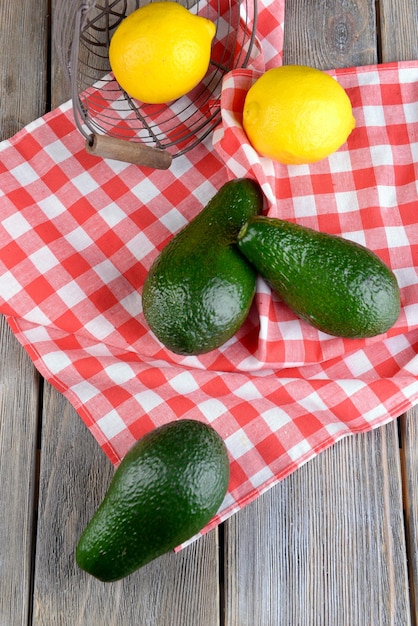 Avocado with lemons on napkin on wooden background