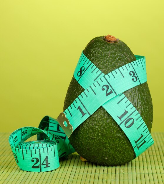 Avocado with measuring tape on green background