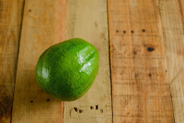 Avocado on wooden table. Isolated avocado in foreground.