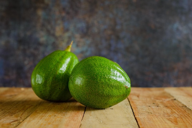 Avocados on wooden table. Isolated avocados in foreground.