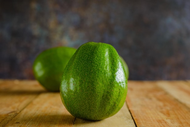 Avocados on wooden table. Isolated avocados in foreground.