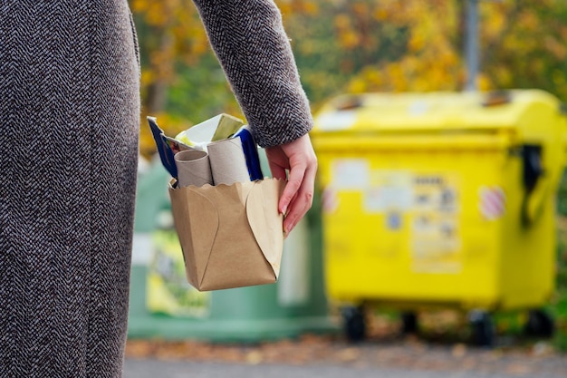 Aware woman separating paper from other waste putting it into green container to save natural resources in Prague Chezh