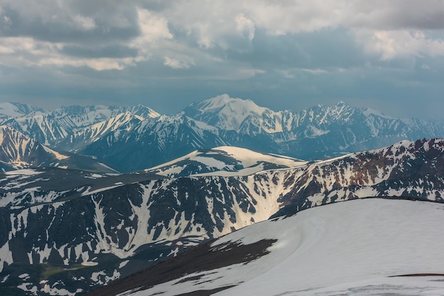 Awesome aerial view to snow mountains under cloudy sky Scenic mountain landscape at very high altitude with cloudiness Atmospheric mountain scenery with beautiful snowy mountain range in overcast