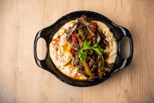 Awrmmah Hummus topping with beef meat served in dish isolated on table top view of arabian food