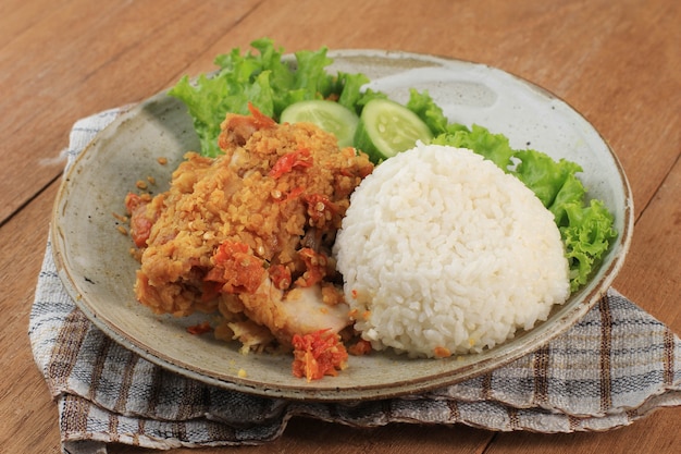 Ayam Geprek is Popular Street Food in Indonesia. Made from Crispy Chicken Smashed in Sambal Bawang (Chilli Garlic Sauce) . Served with Rice and Vegetable