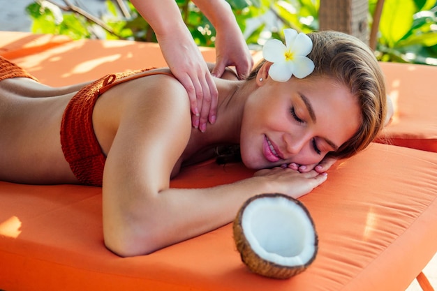 Ayurvedic relaxing massage ,health beauty happy closed eyes woman in spa salon getting massage on the holiday beach.Beautiful girl enjoying day spa resort, lying down on the table treatment procedure