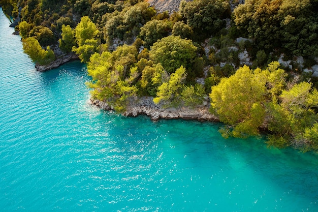 Azure water of the lake and slopes of mountains on a background coast line green trees sun light