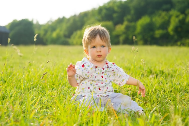 Babe sit on the grass. Little boy playing on the lawn.