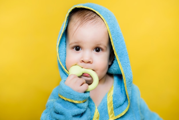 Baby after a bath sits and chews toy