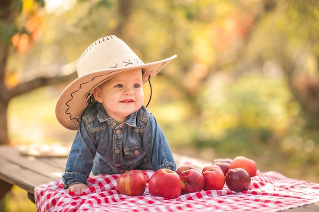 Baby and apples in nature. Funny little kid farmer and apples harvest