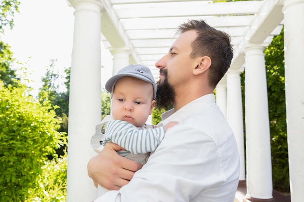 Baby in the arms of dad on a sunny day on a light background