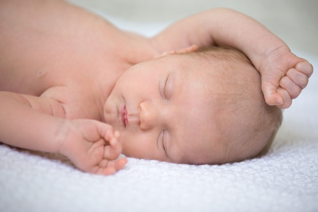 Baby asleep with one arm on the head