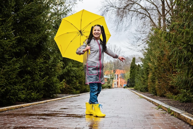 Baby Boomers Happy senior woman in yellow rain coat with yellow umbrella jumping and enjoying life in park