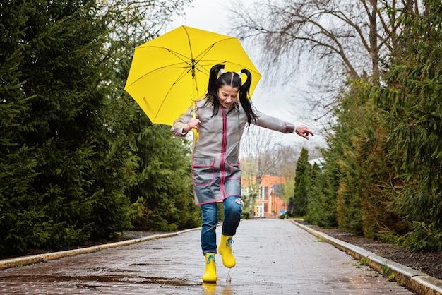 Baby boomers and mental health happy senior woman in yellow rain coat with yellow umbrella jumping