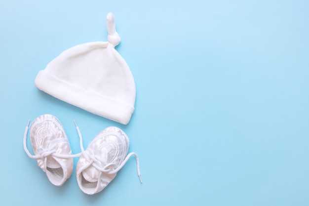 Baby booties and cap on a blue background with copy space