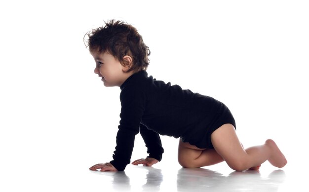 Baby boy crawling Cute overjoyed smiling barefoot child wearing black jumpsuit Isolated portrait shot on white studio background Happy childhood and generation Kid growth and development