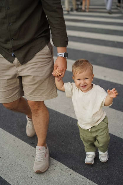 Photo baby boy crossing road on zebra crossing holdingfather by hand in city of saint petersburg russia